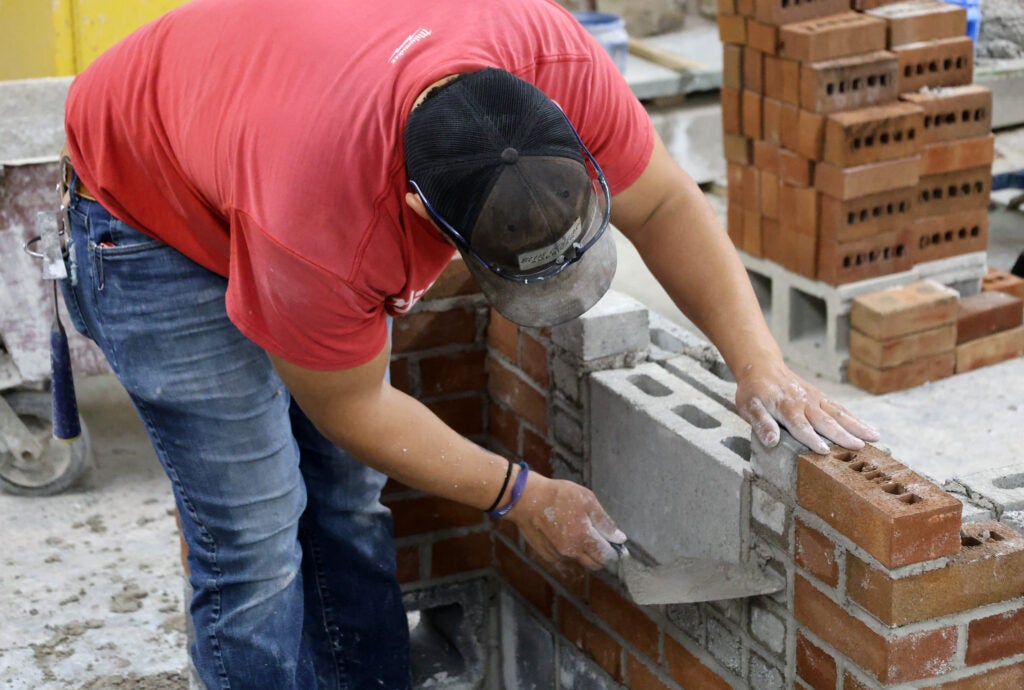 A student practices laying brick in a construction classroom at Alfred State College