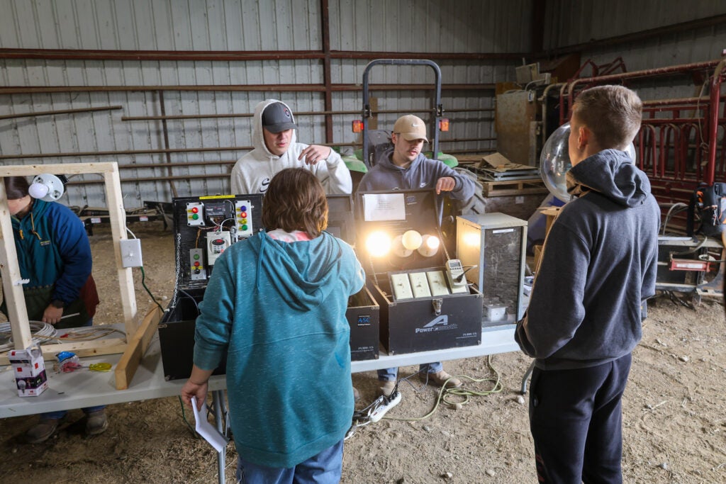 Students learn to operate farming equipment in a training area in a metal barn at Alfred State College