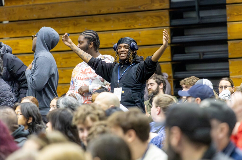 A student stands and holds out their arms in a crowd during an open house event at Alfred State College
