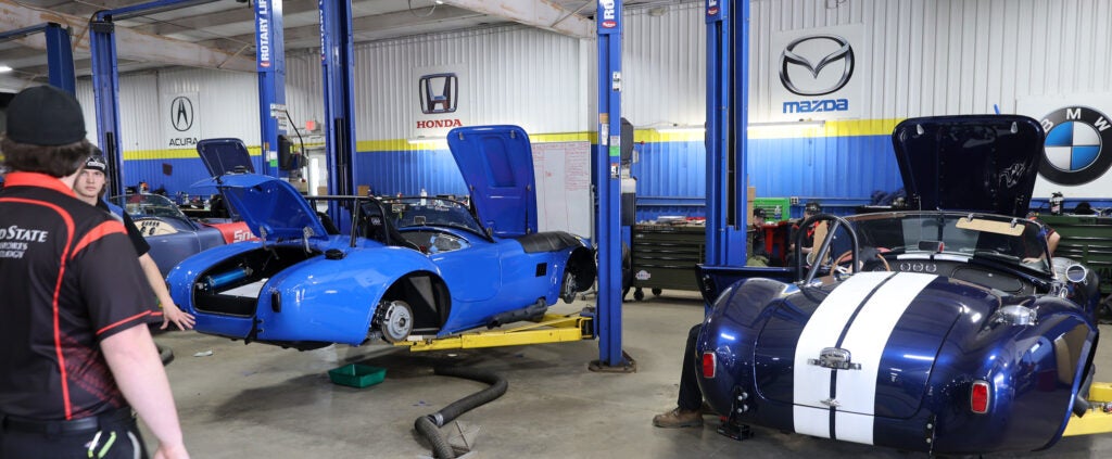 Inside an auto garage featuring blue sports cars on hydraulic lifts, ready for WNY Works students to learn auto repair skills.